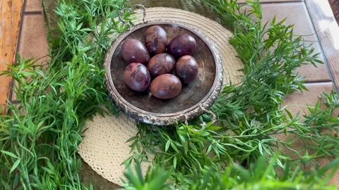 Overhead view of naturally dyed Easter eggs in a vintage metal bowl, surrounded Stock Footage 335923768
