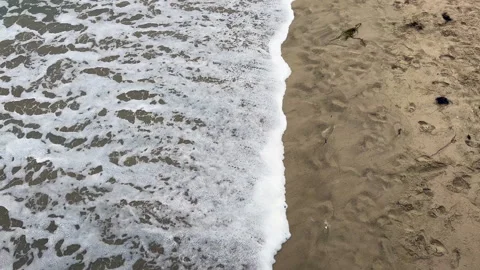 Overhead view of the ocean water waves surf moving over the sandy beach Stock Footage 251239394