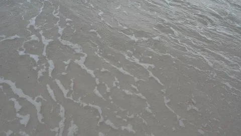 Overhead view of ocean waves and white sea foam washing over a sandy beach Stock Footage 345689592