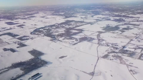 Overhead view out airplane window down to snow covered ground. Jet flying over b Stock Footage 302415339