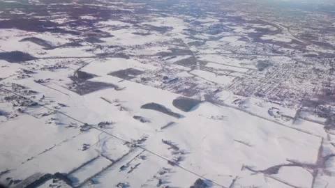 Overhead view out airplane window down to snow covered ground. Jet flying over b Stock Footage 302415367