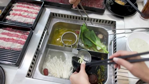 Overhead View of People Cooking Sliced Beef and Vegetables in Hot Pot Stock Footage 334651673