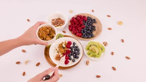 Overhead View of Person Adding Granola to Greek Yogurt Fruit Bowl Stock Footage 338421092