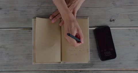 Overhead View Of Person Writing Plan In Open Notebook Beside... 库存影片 332807903
