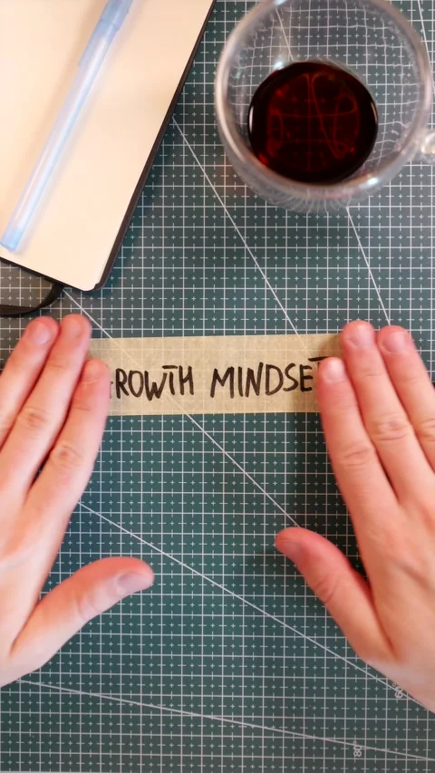 Overhead view of placing GROWTH MINDSET tape sticker near coffee and journal Stock Footage 338183531