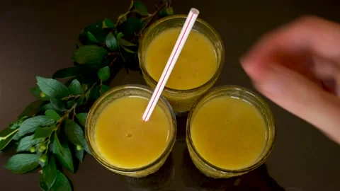 Overhead view of placing red and white straws into orange blended drink. Stock Footage 157818318