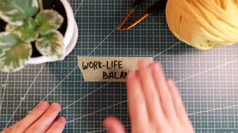 Overhead view of placing WORK-LIFE BALANCE tape near yarn and flowerpot Stock Footage 338183737
