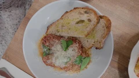 Overhead view of a plate with a meat patty topped with parmesan and basil, Stock Footage 344826188