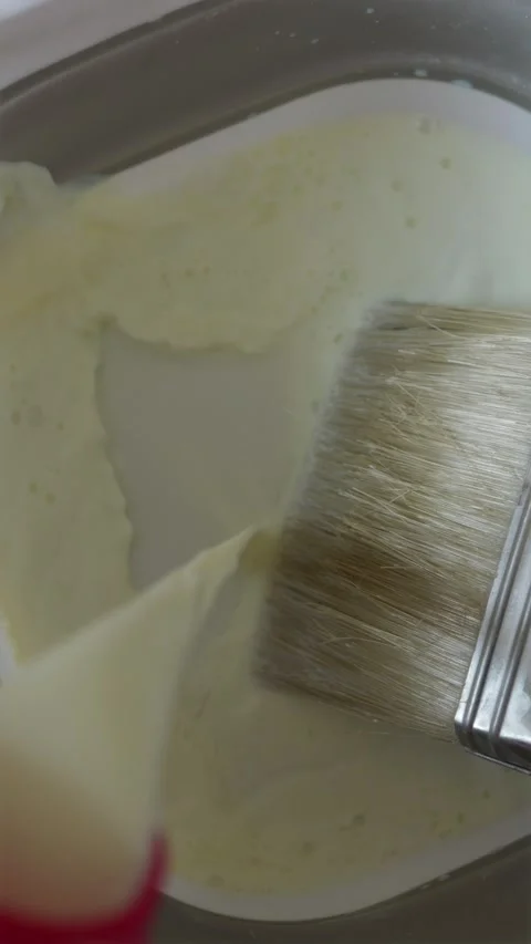Overhead view pouring wall primer into round bowl with brush Stock Footage 340404943
