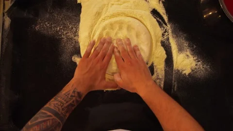 Overhead view of professional cook rolling pizza dough into a flat pizza bread Video stock 149111093
