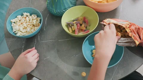 Overhead view putting flavored popcorn back into pack while friend picks popcorn Video stock 318133449