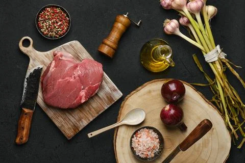 Overhead view of raw beef petite sirloin with ingredients on black background Foto stock