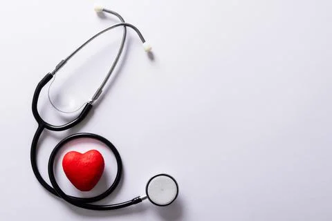 Overhead view of red heart shape with stethoscope against white background, copy Stock Photos