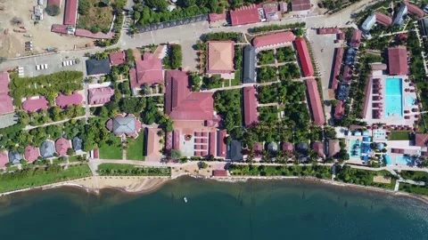 Overhead view of a resort complex by the sea with pools, buildings, and lush Stock Footage 316951990