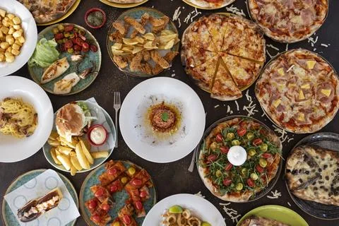 Overhead view of a restaurant table full of various foods Stock Photos