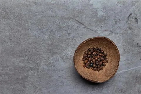 Overhead view of roasted coffee beans in coconut shell on rustic wooden backg Stock Photos