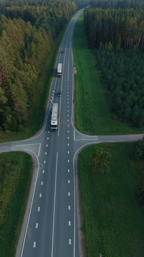 Overhead view of rural road through dense pine forest with truck and car Stock Footage 345529112