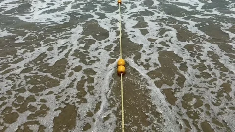 Overhead View of Safety Buoy Rope on the sand in Foamy sea waves. Swimming Stock Footage 342782392