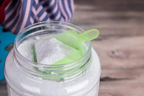 Overhead view of scooper containing laundry powder detergent on wooden surfac Stock Photos