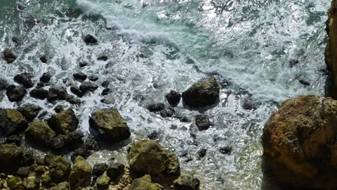 Overhead view of slow motion waves breaking over rocky shore Video stock 168973579