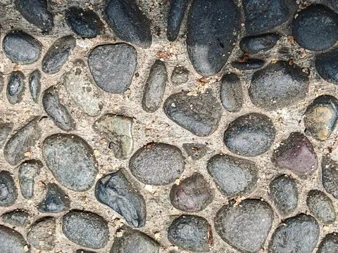Overhead View of Smooth Dark River Pebbles Embedded in Concrete Stock Photos