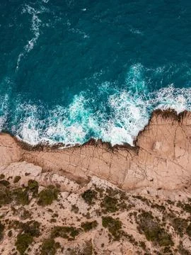 Overhead view of steep cliffs and waves crashing against rocks along coast Stock Photos
