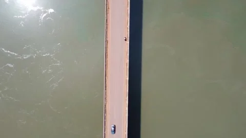 Overhead view of a straight bridge over water with sunlight reflecting on one Stock Footage 317498924