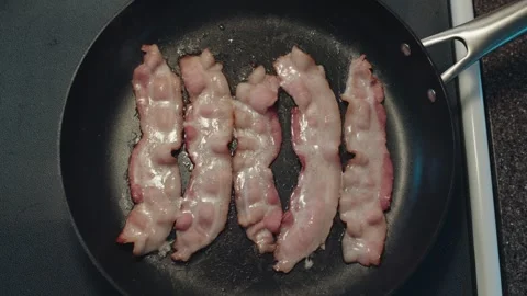 Overhead View of Strips of Bacon Slowly Cooking in a Frying Pan Stock Footage 318566525