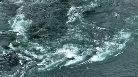 Overhead view of strong ocean current forming eddies and whirlpools in water Stock Footage 243626930