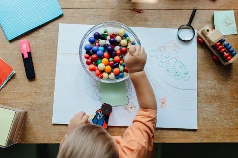 Overhead view of a toddler boy picking a bead out of a bowl Stock Photos