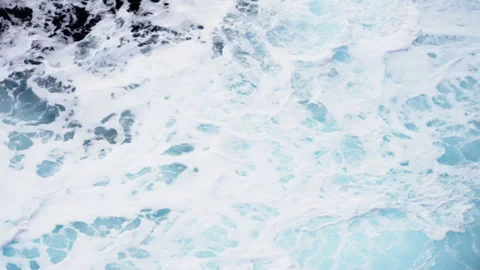 Overhead view of turquoise ocean surface with swirling waves and dense sea foam Stock Footage 316775678