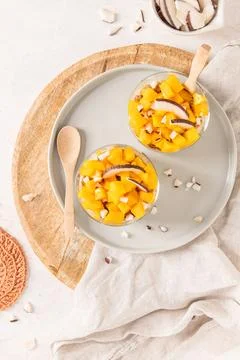 Overhead view of two glass jars filled with fresh mango chunks and coconut .. Stock Photos