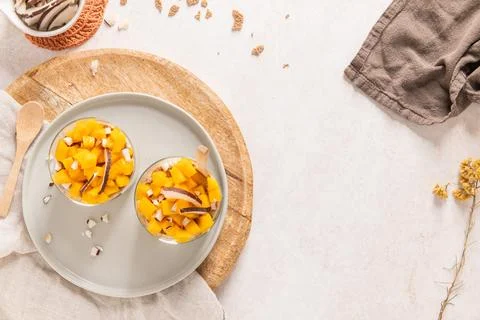Overhead view of two glass jars filled with fresh mango chunks and coconut .. Stock Photos