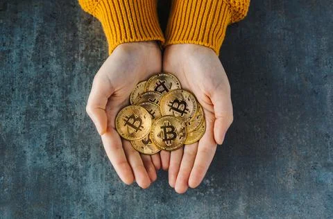 Overhead view of two hands full of bitcoins on a textured background. Golden  Fotos de archivo