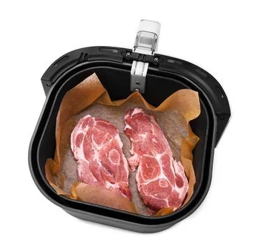 An overhead view of two raw pork neck steaks on parchment paper inside the .. Foto stock