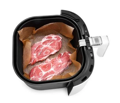 An overhead view of two raw pork neck steaks on parchment paper inside the .. Foto stock