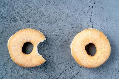 Overhead view of two sugar ring donuts with one single bite taken Stock Photos