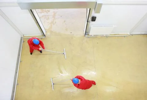 Overhead view of two workers cleaning floor in industrial building Stock Photos