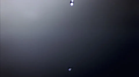 Overhead view of ultra-slow motion drop falling onto dark water and creating Stock Footage