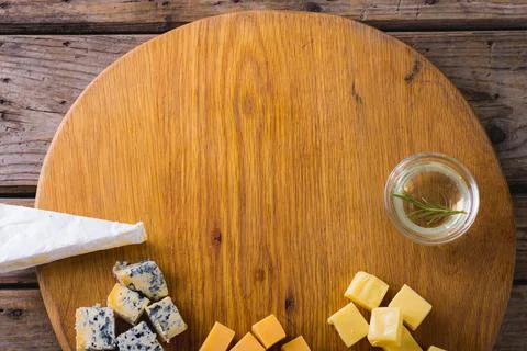 Overhead view of various cheese with rosemary on wooden board, copy space Stock Photos