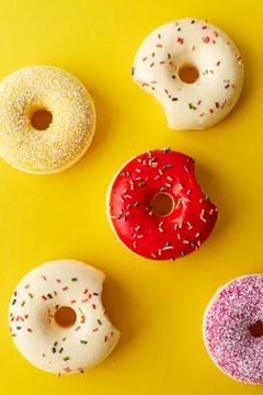 Overhead view of various donuts with confetti arranged on colored background Stock Photos