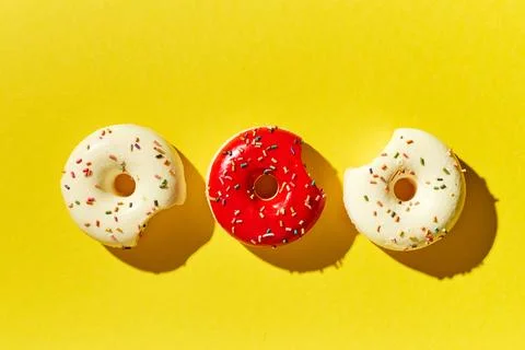 Overhead view of various donuts with confetti arranged on colored background Stock Photos