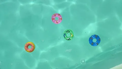 Overhead view of vibrant donut rings gently drifting in a sunlit turquoise .. Stock Footage 334318554