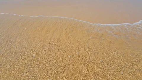 Overhead view of a wave in slow motion arriving at a sandy beach. Background or Stock Footage 253723028