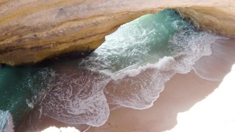 Overhead view of waves breaking on sandy beach inside benagil cave Stock Footage 168973708
