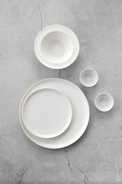 Overhead view of white tableware on grey background Foto stock