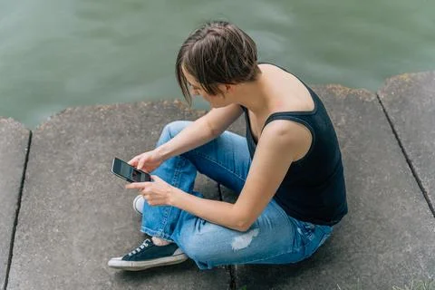 Overhead view of woman 40s using smartphone on urban riverbank Stock Photos