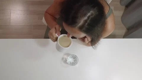 Overhead view woman in olive top drinking coffee at white table Stock Footage 323123774