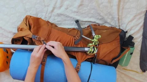 Overhead view of woman securing ice axe to hiking backpack, preparing technical Stock Footage 333766647