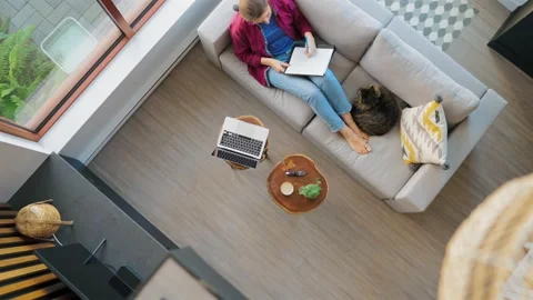 Overhead view of woman writing notes, lying on couch at home Stock Footage 256043587